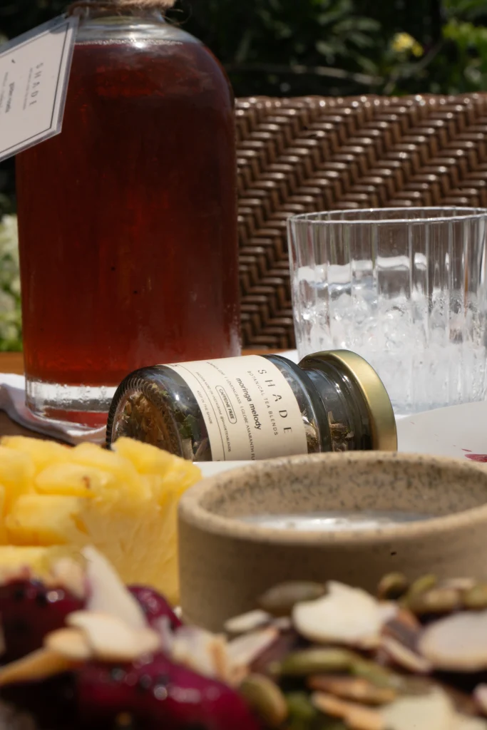 SHADE_Botanicals_-_Loose_Leaf_Tea_Blends_-_Drinking_Lifetyle_-_70_mL_Recycled_Glass_Jar_and_Iced_Tea_Bottle_-_Golden_Rosella_and_Moringa_Melody_Variant